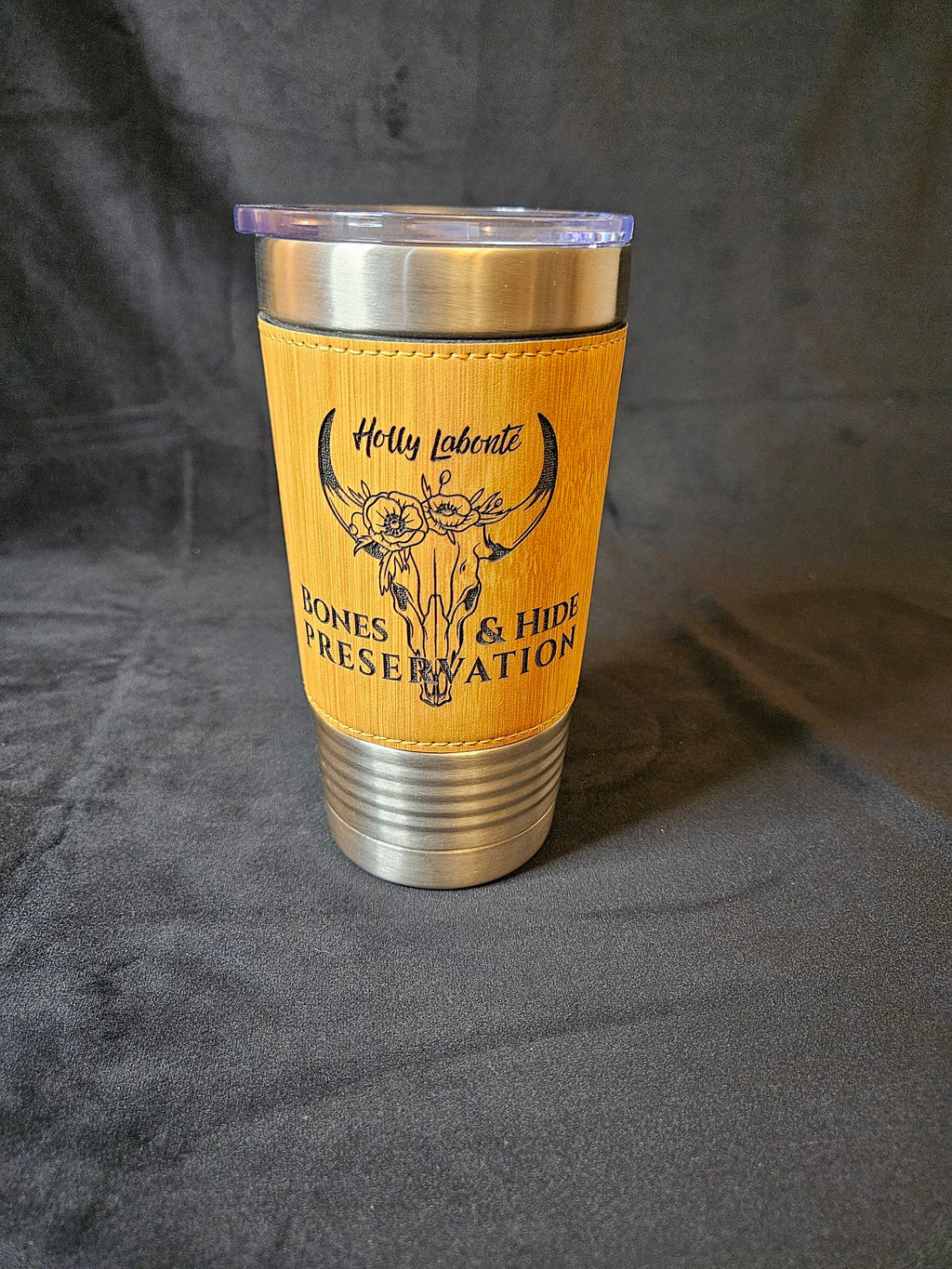 Tan leather-wrapped tumbler with engraved female longhorn skull logo, front