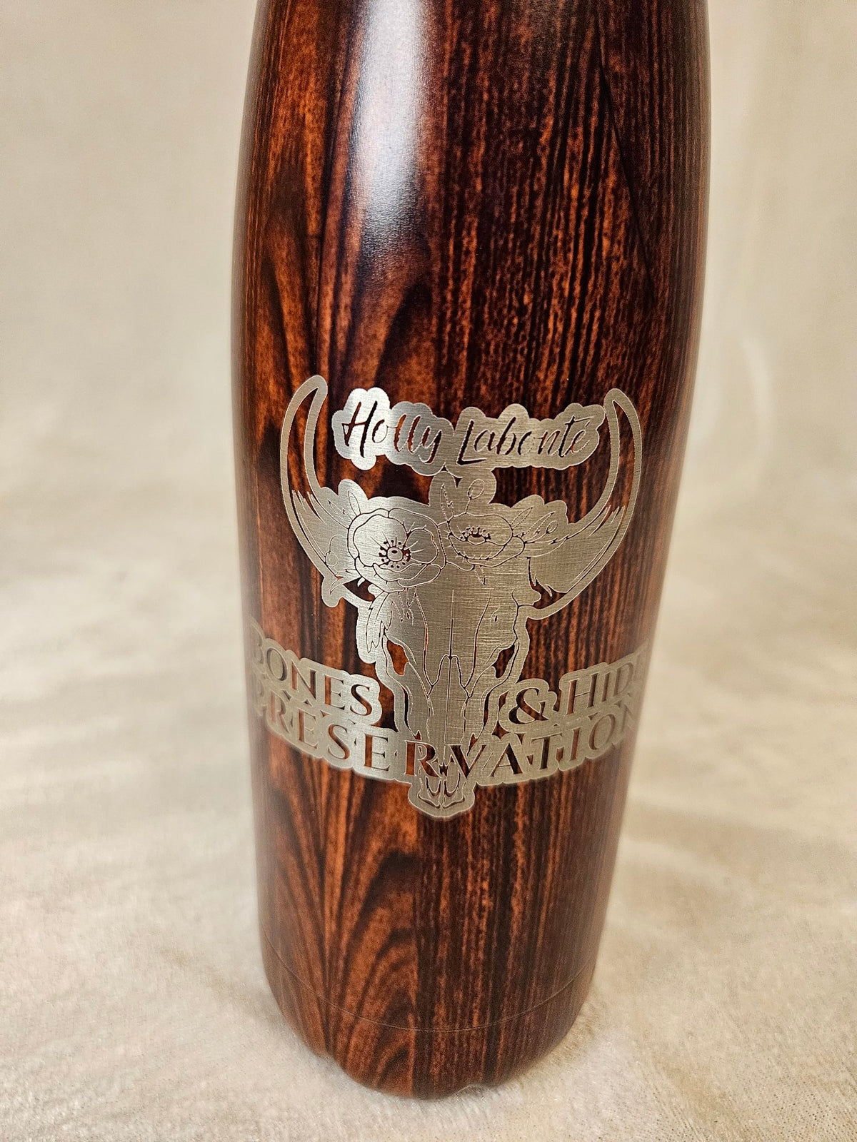Close-up of engraved female logo on wood-grain water bottle
